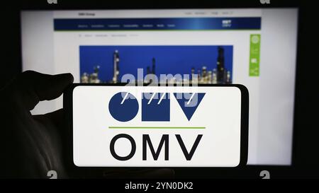 Stuttgart, Allemagne, 03-16-03 2024 : personne tenant un smartphone avec le logo de la société pétrolière et gazière autrichienne OMV Aktiengesellschaft devant le site web. Mise au point Banque D'Images