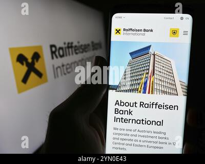 Stuttgart, Allemagne, 03-16-2024 : personne tenant un téléphone portable avec la page web de la société autrichienne Raiffeisen Bank International AG (RBI) avec le logo. Concentrez-vous sur c Banque D'Images