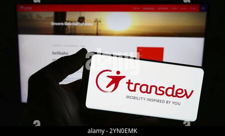 Stuttgart, Allemagne, 03-05-2024 : personne tenant un smartphone avec le logo de la société allemande de transport public Transdev GmbH devant le site. Concentrez-vous sur pho Banque D'Images