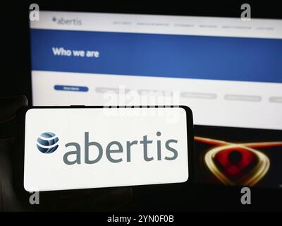 Stuttgart, Allemagne, 04-13-04 2024 : personne tenant un smartphone avec le logo de la société espagnole de péage Abertis Infraestructuras S.A. en face du site. FO Banque D'Images