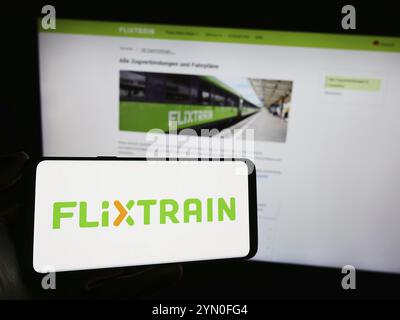 Stuttgart, Allemagne, 03-05-2024 : personne tenant un téléphone portable avec le logo de la compagnie de chemin de fer allemande FlixTrain devant la page web de l'entreprise. Banque D'Images