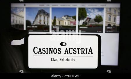 Stuttgart, Allemagne, 04-05-2024 : personne tenant un téléphone portable avec le logo de la société de jeux autrichienne casinos Austria AG en face de la page web de l'entreprise. Mise au point Banque D'Images