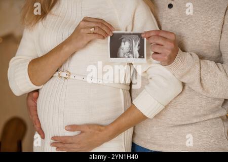 Les futurs parents réconfortants tenant une image échographique dans un cadre confortable. Banque D'Images