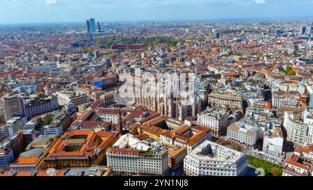Vue aérienne à couper le souffle de l'emblématique cathédrale Duomo de Milan entourée d'un paysage urbain animé, mettant en valeur l'architecture historique et la vie urbaine sous-jacente Banque D'Images