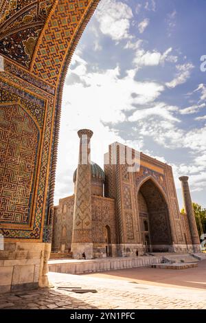 Une perspective fascinante d'une madrasa Registan Square parfaitement encadrée par l'arc d'une autre, mettant en évidence des conceptions complexes et un charme historique. Banque D'Images