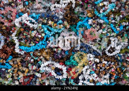 Une variété de colliers et bracelets de perles colorés disposés sur une surface. Certaines perles sont rondes et lisses, tandis que d'autres sont de forme irrégulière. Banque D'Images