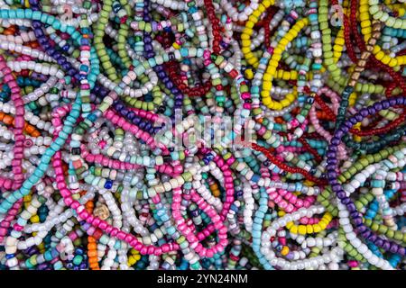 Une variété de colliers et bracelets de perles colorés disposés sur une surface. Certaines perles sont rondes et lisses, tandis que d'autres sont de forme irrégulière. Banque D'Images