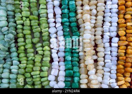 Une variété de colliers et bracelets de perles colorés disposés sur une surface. Certaines perles sont rondes et lisses, tandis que d'autres sont de forme irrégulière. Banque D'Images