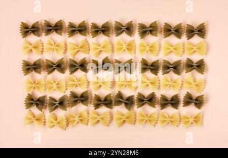 Pâtes farfalle disposées en rangées sur fond Uni rose Banque D'Images