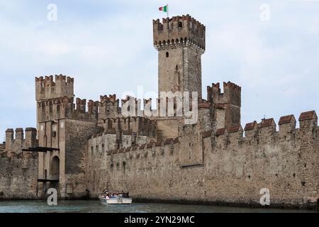 SIRMIONE, ITALIE - 13 MAI 2018 : un bateau avec des touristes non identifiés est situé près des murs du château médiéval de Scaliger sur le lac de Garde. Banque D'Images