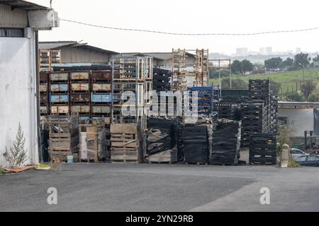 Caisses et palettes en métal et en bois empilées dans une cour d'entrepôt industrielle, stockant diverses marchandises Banque D'Images