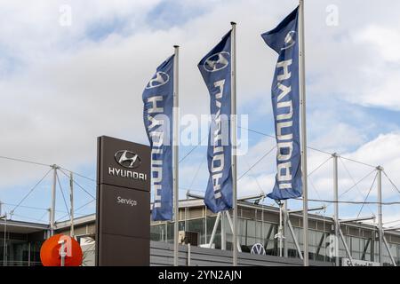 Drapeaux Hyundai agités devant un bâtiment de concession par temps nuageux Banque D'Images