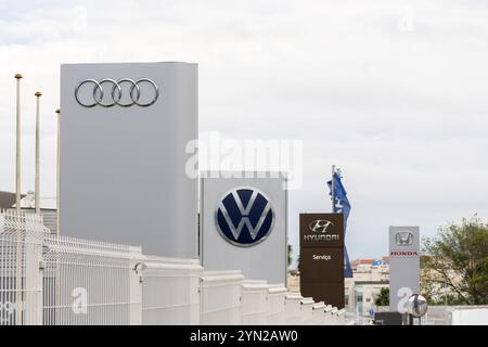 Quatre logos de marques automobiles sur les enseignes des concessionnaires représentant la concurrence de l'industrie automobile Banque D'Images