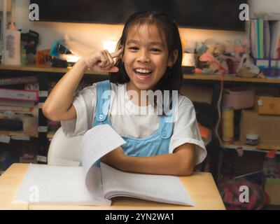 Homeschool petite fille asiatique étudiante apprenant attentivement, lisant et étudiant avec un crayon à la main et apprenant. Banque D'Images