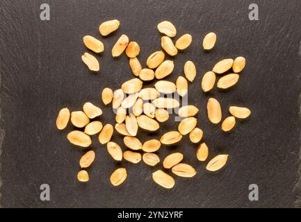 Cacahuètes pelées, grillées sur une pierre d'ardoise, macro, vue de dessus. Banque D'Images