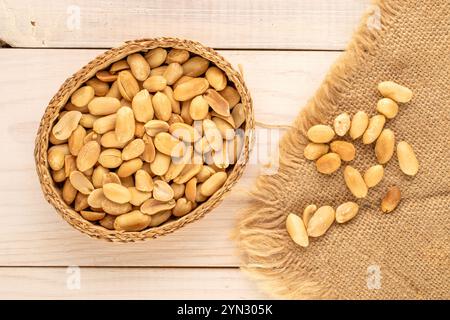 Cacahuètes pelées, rôties dans une assiette de paille sur une table en bois, gros plan, vue de dessus. Banque D'Images