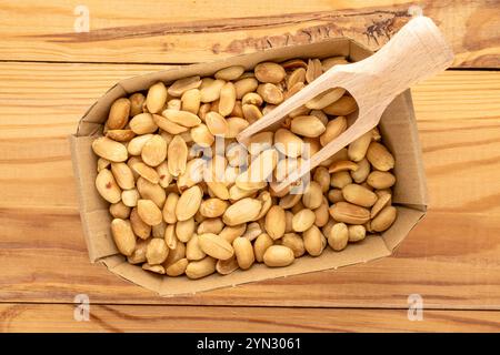 Cacahuètes pelées et rôties dans une assiette en papier sur une table en bois, gros plan, vue de dessus. Banque D'Images