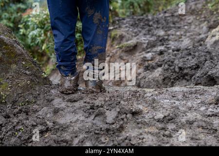 Un gros plan d'un sentier boueux et d'un homme qui a des bottes boueuses, debout immobile à Khumbu, Népal. Banque D'Images