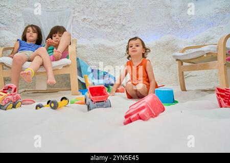 Les enfants jouent avec des jouets dans une salle de jeux remplie de sable Banque D'Images