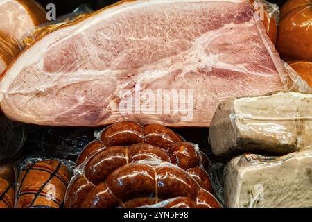 Divers jambons et saucisses en gros plan d'emballage sous vide dans la vitrine en verre de boucherie. Banque D'Images