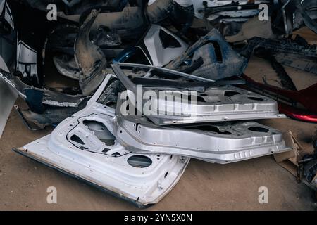 Pile de portes en vente pour les pièces de rechange. Gros plan des portes de voiture accidentées empilées chez le mécanicien de carrosserie. Échange de pièces détachées automobiles d'occasion. Beaucoup de blanc usagé Banque D'Images