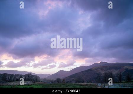 Keswick, Cumbria, 24 novembre 2024. Des nuages spectaculaires coulent au-dessus des Fells de Cumbria au crépuscule près de Keswick alors que les restes de la tempête Bert passent au-dessus du Lake District. Le temps consistait en vents violents et en averses au coucher du soleil. Crédit : Julian Eales/Alamy Live News Banque D'Images