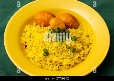 Goiania, Goias, Brésil – 24 novembre 2024 : une assiette jaune avec du riz et trois pequis sur une nappe verte. Nourriture typique de Goias. Banque D'Images