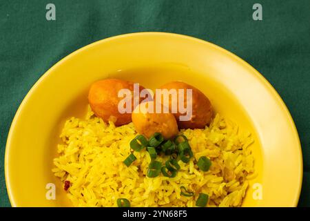 Goiania, Goias, Brésil – 24 novembre 2024 : une assiette jaune avec du riz et trois pequis sur une nappe verte. Nourriture typique de Goias. Banque D'Images