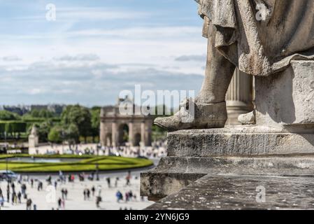 Le pied d'une statue sur le toit du Palais du Louvre avec un arc de triomphe en arrière-plan, Paris, France, Europe Banque D'Images