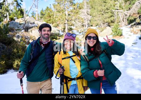 Portrait joyeux de trois amis multirraciaux randonnant dans une forêt enneigée pendant les vacances d'hiver. Banque D'Images