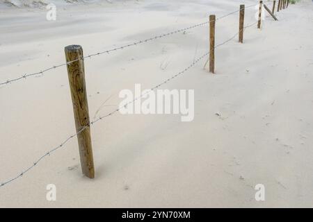 Clôture de fil de fer barbelé sur la plage de sable Banque D'Images