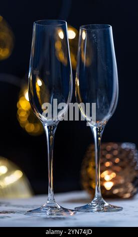 concept de célébration de noël et du nouvel an, verres de champagne sur fond de bougies et de guirlandes colorées, ambiance traditionnelle chaleureuse à la maison Banque D'Images