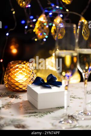 concept de célébration de noël et du nouvel an, verres de champagne sur fond de bougies et de guirlandes colorées, ambiance traditionnelle chaleureuse à la maison Banque D'Images