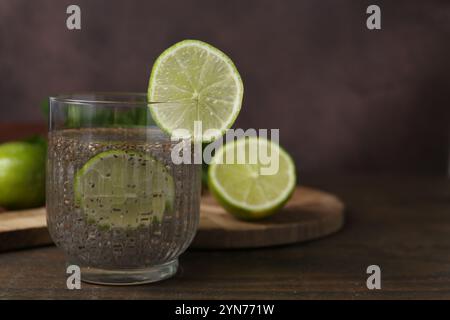 Verre de boisson avec des graines de chia et citron vert sur une table en bois, gros plan. Espace pour le texte Banque D'Images