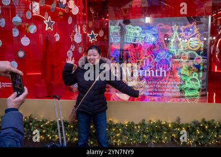 New York, États-Unis. 24 novembre 2024. NEW YORK, NEW YORK - 24 NOVEMBRE : une femme pose devant la vitrine des fêtes Macy's au magasin phare Macy's Herald Square sur la 34e rue à Midtown Manhattan le 24 novembre 2024 à New York. Crédit : Ron Adar/Alamy Live News Banque D'Images