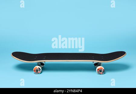 Un skateboard sur fond bleu clair. EQUIPEMENT sportif Banque D'Images