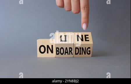 Symbole d'intégration en ligne. Homme d'affaires points de main à des cubes en bois tournés avec des mots Online Onboarding. Beau fond gris. Affaires et en ligne Banque D'Images