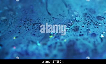 Éclaboussure d'encre brillante. Texture scintillante humide. Flou bleu scintillant particules de paillettes peinture liquide brillant goutte à goutte fond d'art abstrait avec des lumières bokeh. Banque D'Images