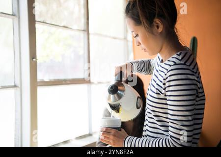 Femme versant de l'eau chaude d'une casserole Banque D'Images