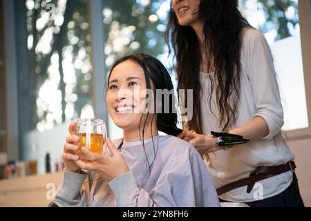 Femme ayant une tasse de thé dans un salon de coiffure Banque D'Images
