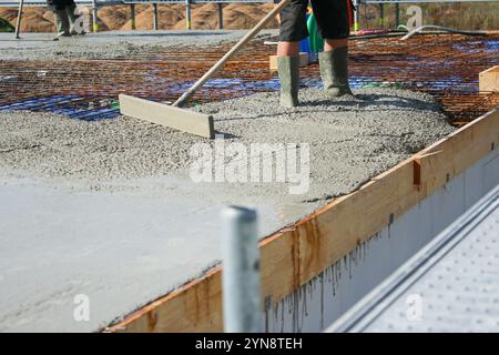 Ouvriers remplissant le sol du deuxième étage avec le béton, le noyau et le bâtiment de construction de coquille Banque D'Images