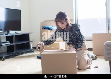 Femme dans la vingtaine mettant du ruban adhésif sur du carton Banque D'Images