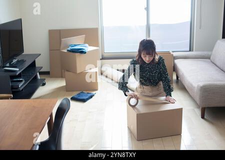 Femme dans la vingtaine mettant du ruban adhésif sur du carton Banque D'Images