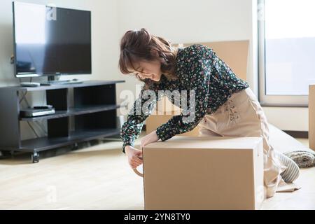 Femme dans la vingtaine mettant du ruban adhésif sur du carton Banque D'Images