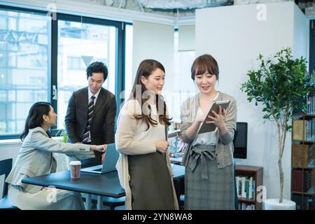 Hommes et femmes souriant et parlant pendant le travail de bureau Banque D'Images