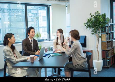Hommes et femmes souriant et parlant pendant le travail de bureau Banque D'Images