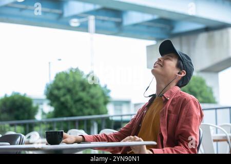 Homme dans la vingtaine souriant au café Banque D'Images