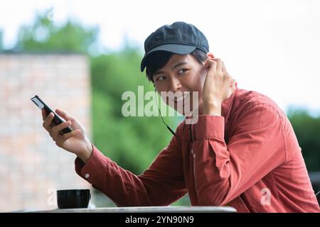 Homme dans la vingtaine souriant au café Banque D'Images