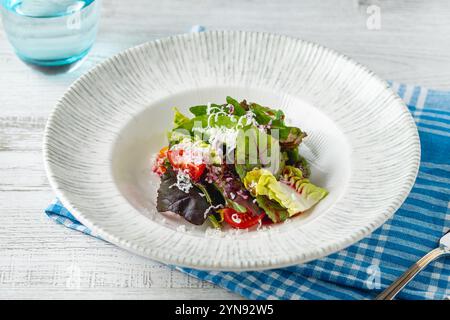 Salade de légumes verts de saison mélangés sur une assiette en porcelaine blanche Banque D'Images