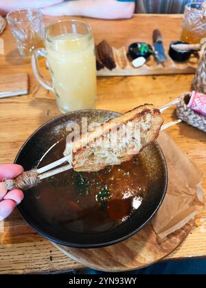 Un repas rustique chaleureux et accueillant avec une soupe savoureuse avec du pain broché, sur une table en bois confortable, accompagné d'une boisson rafraîchissante et d'un assortiment Banque D'Images